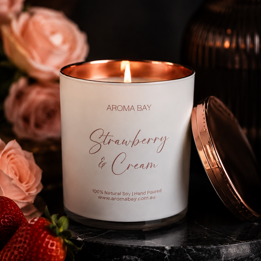 Aroma Bay Strawberry & Cream candle with roses and strawberries on a dark surface