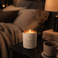 Candle and mug on a bedside table with a cozy bedroom setting