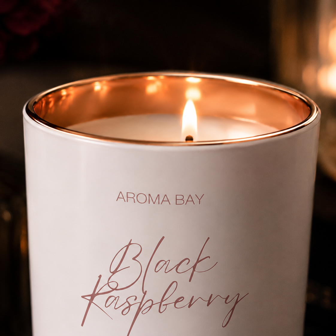 Aroma Bay Black Raspberry candle with a warm glow in a dark setting