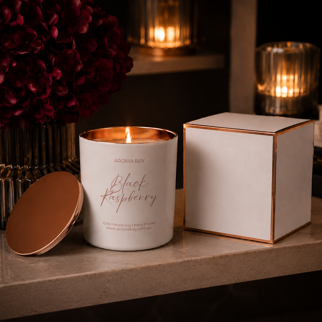 White candle with 'Black Raspberry' text on a wooden surface with a box and decorative items.