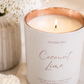 Aroma Bay coconut lime candle with a rose gold lid on a white surface with flowers in the background